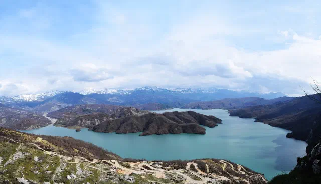 Het turquoise stuwmeer van Bovilla met besneeuwde bergen, op een half uur rijden van Tirana