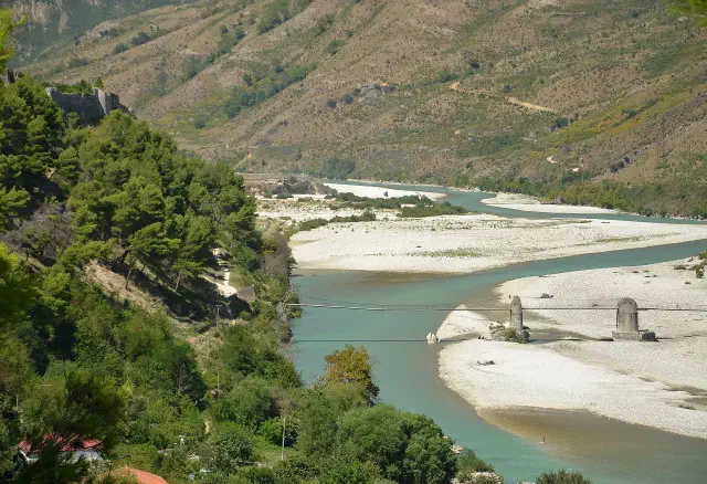 De wijd vertakte Vjosa bij Tepelenë, met de oude hangbrug over de rivier